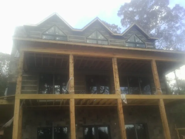 Dormers and porch framing on a large log home under construction — Roof Coating work by our crew in Middlebury Center