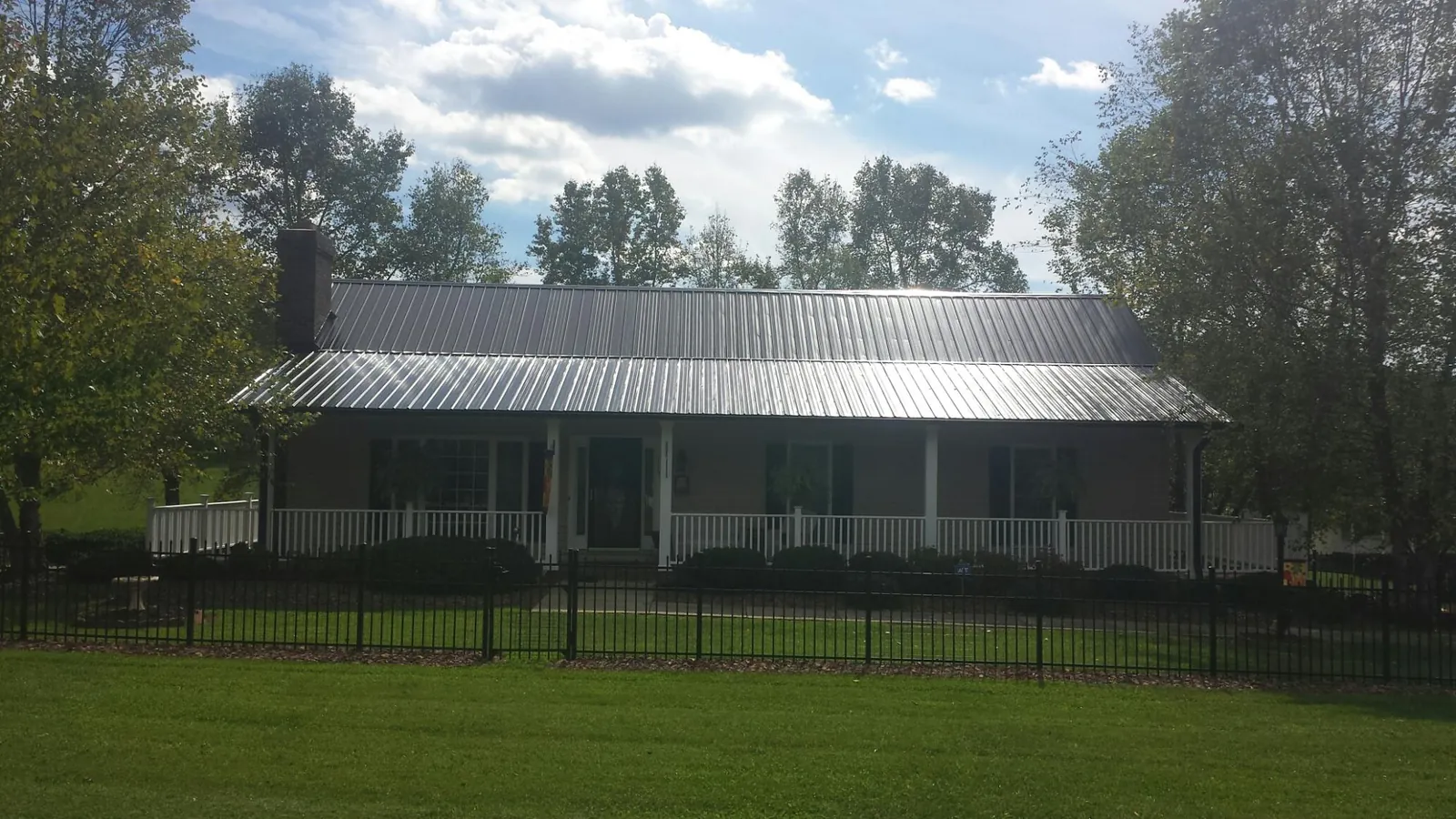 Gray metal roof on a brick ranch with a full width front porch — Gutter Guard Installation work by our crew in Middlebury Center