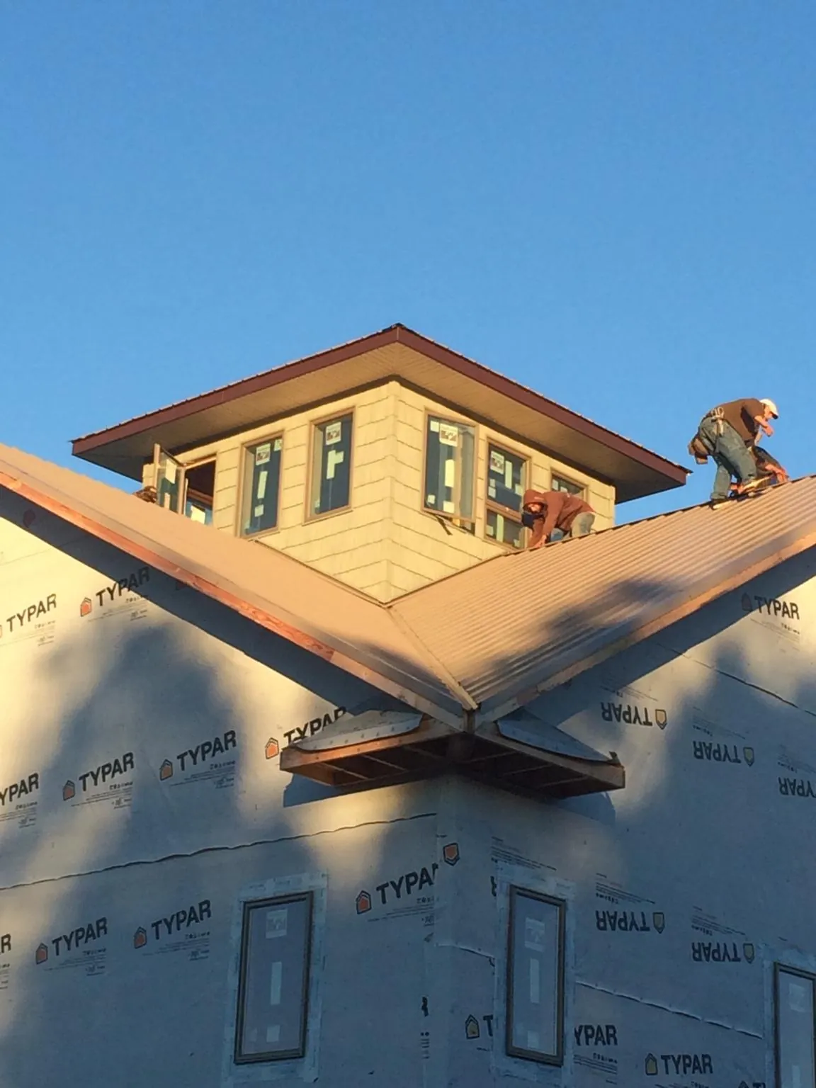 Roofers working around a rooftop cupola on a new metal roof at sunset — Roof Waterproofing in Middlebury Center by Roofing Brothers